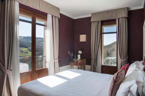 a bedroom with a bed and a large window at La Posta Hotel & Thermal Spa in Bagno Vignoni