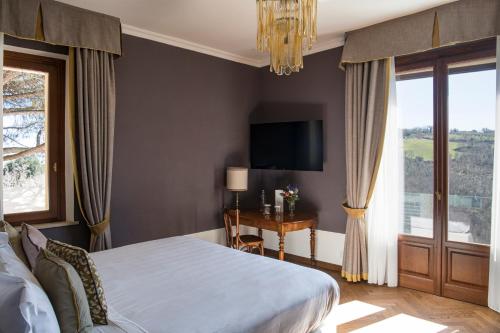 a bedroom with a bed and a desk and a television at La Posta Hotel & Thermal Spa in Bagno Vignoni