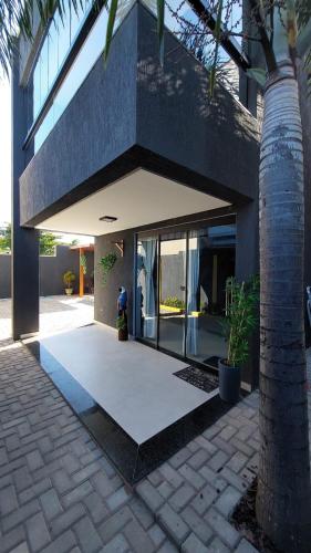 a house with glass doors and a palm tree at Casa com vista para o mar e piscina em Milagres in São Miguel dos Milagres