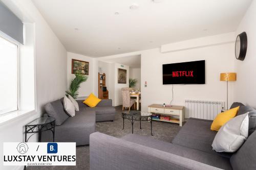 a living room with couches and a tv on the wall at Bright and Spacious 2BR Maisonette Sleeps 8, Game Room, 5 mins to Brighton Beach and City Centre in Brighton & Hove
