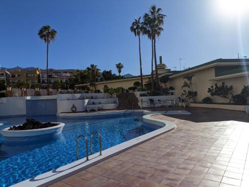 a swimming pool in front of a house with palm trees at Brisa del Teide - Free parking in Playa Paraiso