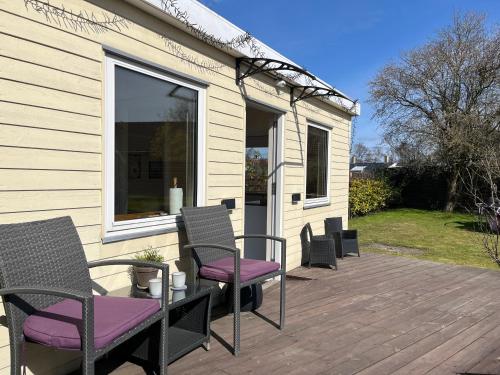 a patio with chairs and a table with purple cushions at Cosy Guesthouse near Copenhagen in Rødovre