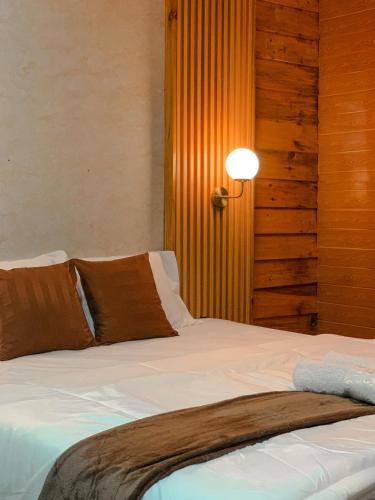 a bedroom with a bed with white sheets and brown pillows at Avana Cabin Sikunir Lake View in Kejajar