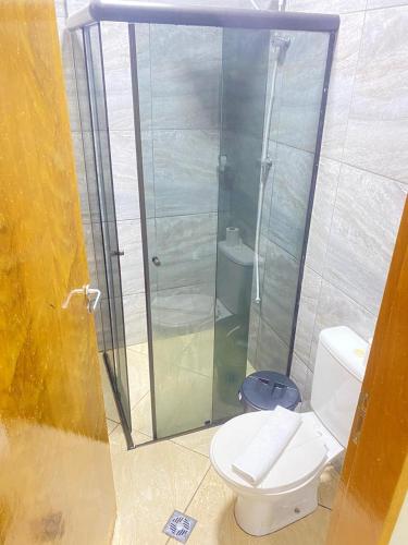 a bathroom with a toilet and a glass shower at Pousada Sagrada Devoção in Aparecida
