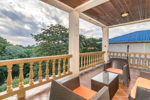 a balcony with chairs and tables and a view of the forest at Tropical Sunset at Sunset Villas in West End in Roatan