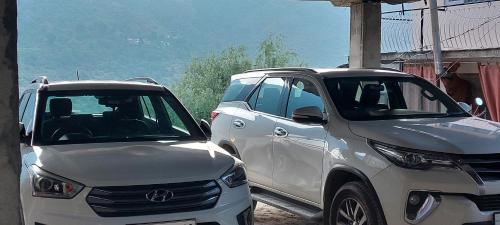 two white cars parked next to each other at Mountain Heaven Mcleodganj in Dharmsala