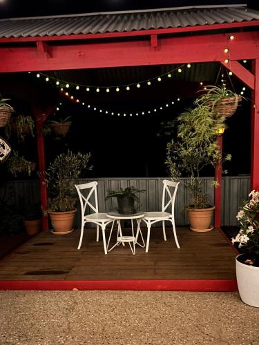 two white chairs and a table on a wooden deck at Sage Cottage in Cowaramup