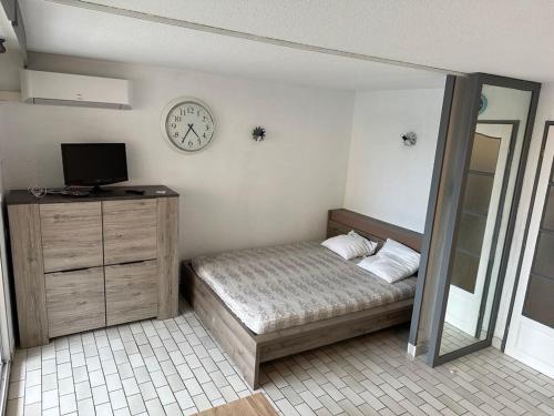 une chambre avec un lit et une horloge au mur dans l'établissement Appart:résidence avec piscine, au Cap d'Agde