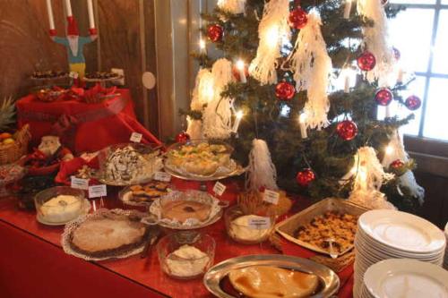 a table topped with pies and other food next to a christmas tree at Forsbacka Wärdshus in Forsbacka