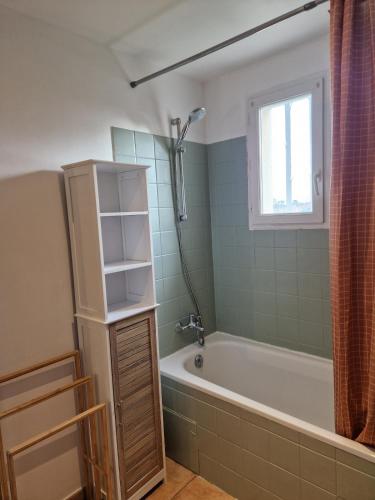 une salle de bain avec une baignoire et une fenêtre dans l'établissement Maison Saint Pierre Oleron, à Saint-Pierre-dʼOléron