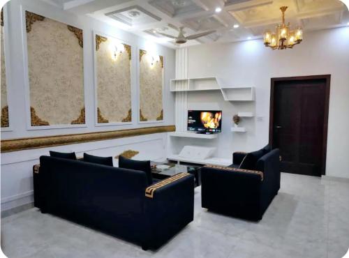 a living room with two chairs and a tv at Furnished Private 1 BR Ground Floor in DHA in Lahore