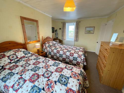 a bedroom with two beds and a quilt at Traditional Cottage with Beautiful Views - Pass the Keys in Isle of Whithorn