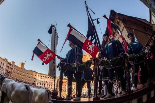a statue of a group of people holding flags at La Martinella by Palazzo Bianchini in Siena