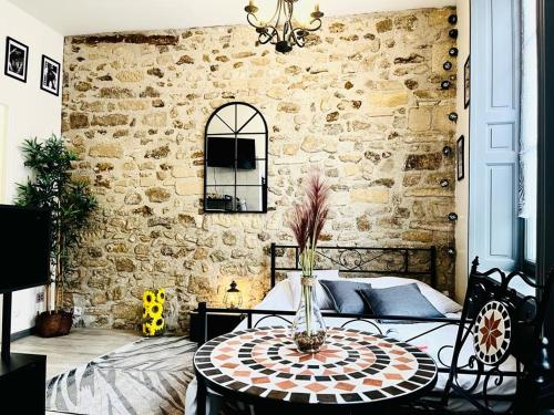 Cette chambre comprend un lit, une table et un mur en pierre. dans l'établissement capucin 2 super studio au pied de la cathédrale, à Reims