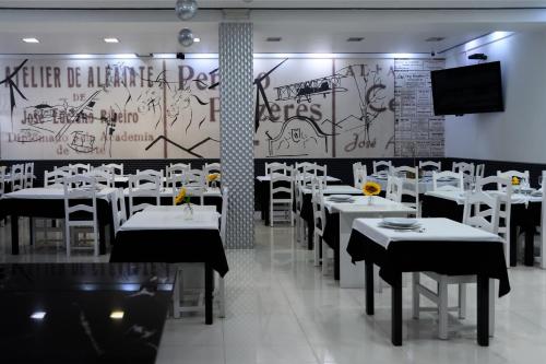 a restaurant with white tables and chairs and a wall with graffiti at Hotel Alendouro in Macedo de Cavaleiros