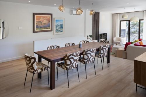 a dining room and living room with a wooden table and chairs at Luxurious 1 bedroom in Camps Bay villa with a pool in Cape Town