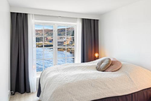 una camera da letto con un letto con una grande finestra di Komfortable Ferieleiligheter med Sjøutsikt a Stadlandet