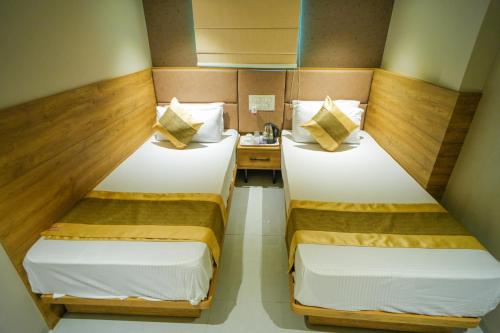 two twin beds in a small room with a table at Hotel Skylink Hospitality Mahalaxmi in Mumbai
