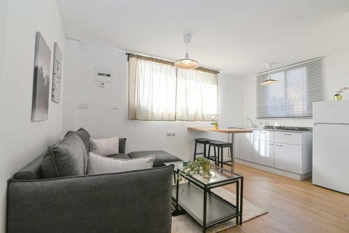 a living room with a couch and a table and a kitchen at הדירה בלבן פלאי in H̱adera