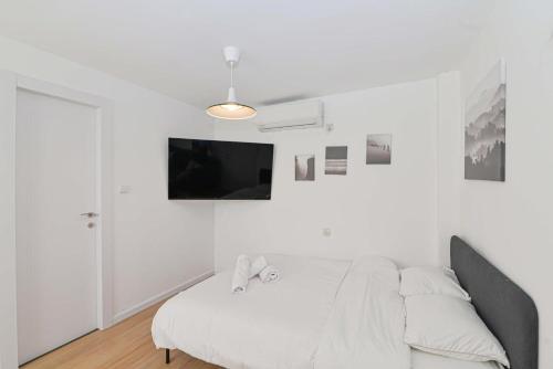 a white bedroom with a bed and a flat screen tv at הדירה בלבן פלאי in H̱adera
