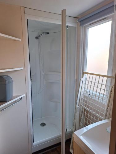 une douche avec une porte vitrée dans une salle de bain dans l'établissement Mobil home 6 personnes, au Barcarès