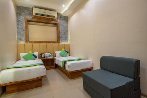 a small room with two beds and a chair at Hotel Skylink Hospitality Mahalaxmi in Mumbai