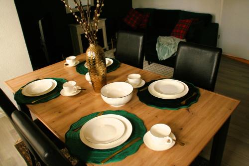 a wooden table with white plates and a vase at Le petit Charme - Wohnen in einer historischen Villa in Suhl