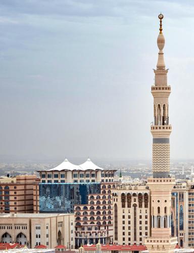 a mosque with a tall tower in the city at Pullman Zamzam Madina in Al Madinah