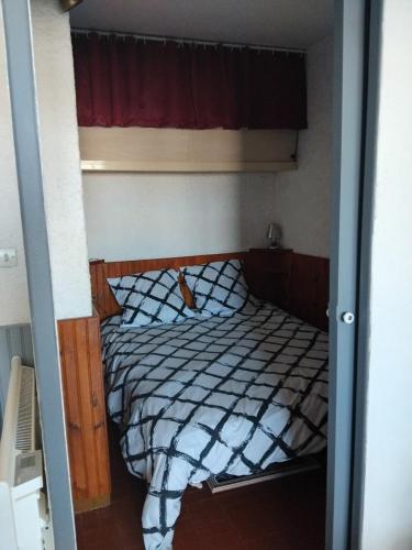 un petit lit dans une chambre avec une fenêtre dans l'établissement STUDIO Bis - PLAGE, à Port-la-Nouvelle