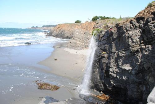 a waterfall on a cliff next to a beach at Stunning views near beaches and bluff in Sea Ranch