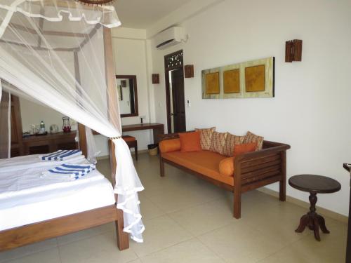 a bedroom with a bed and a couch and a table at Lanka Beach Boutique Bungalows & Grand Villa in Tangalle