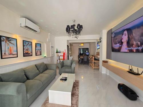 a living room with a couch and a flat screen tv at The Bliss House Bangsaen in Ban Laem Thaen