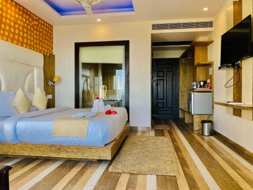 a bedroom with a large bed and a television at Aachman Nature Valley Resort Mashobra BY NAINA STAYCATION- Private Parking - Balcony and valley view Rooms in Shimla