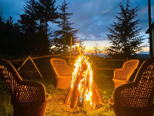 a fire pit with chairs around it with the sunset at Aachman Nature Valley Resort Mashobra BY NAINA STAYCATION- Private Parking - Balcony and valley view Rooms in Shimla