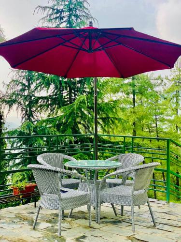 a table and chairs with a purple umbrella on a patio at Aachman Nature Valley Resort Mashobra BY NAINA STAYCATION- Private Parking - Balcony and valley view Rooms in Shimla