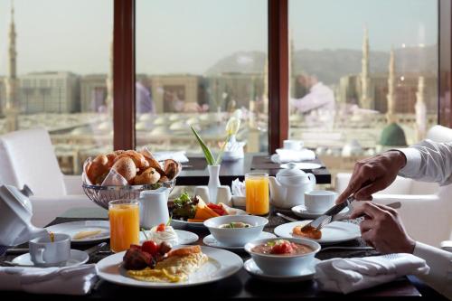 a table with breakfast food on it with a view at Pullman Zamzam Madina in Al Madinah