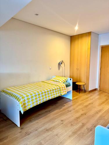 a bedroom with a yellow and white bed and a table at Âmbar Guest House in Braga