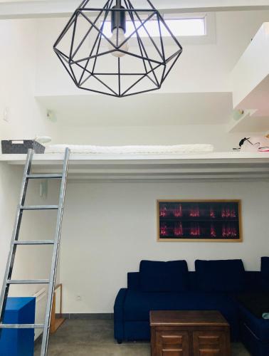 un salon avec un canapé bleu et un lustre dans l'établissement Atelier des lilas, aux Lilas