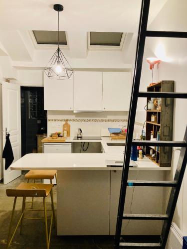 - une cuisine avec des placards blancs, un évier et une échelle dans l'établissement Atelier des lilas, aux Lilas