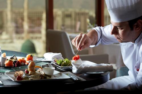 a chef sitting at a table with a plate of food at Pullman Zamzam Madina in Al Madinah