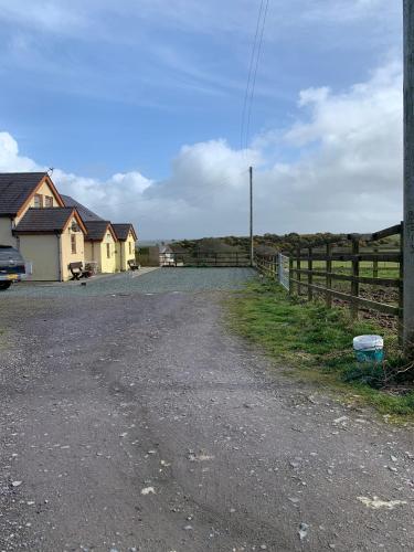 una strada sterrata con una casa e una recinzione di Anglesey Quiet cottage otto a Gwalchmai