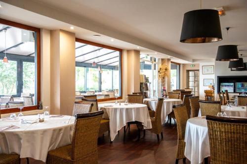 un restaurant avec des tables et des chaises blanches et des fenêtres dans l'établissement Hôtel - Restaurant La Chaloupe, à Le Port-des-Barques