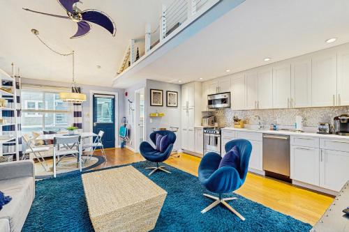 a living room with blue chairs and a kitchen at Provincetown Waterfront Studio in Provincetown