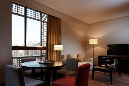 a living room with a table and chairs and a couch at Pullman Zamzam Madina in Al Madinah