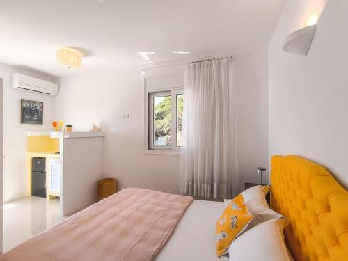 1 dormitorio con 1 cama con cabecero amarillo y ventana en Villa Fanari, en Kanapitsa