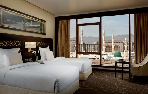 a hotel room with two beds and a large window at Pullman Zamzam Madina in Al Madinah