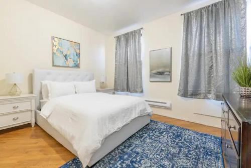 a bedroom with a white bed and a blue rug at Prime Location Upper Manhattan Furnished Apartment in New York