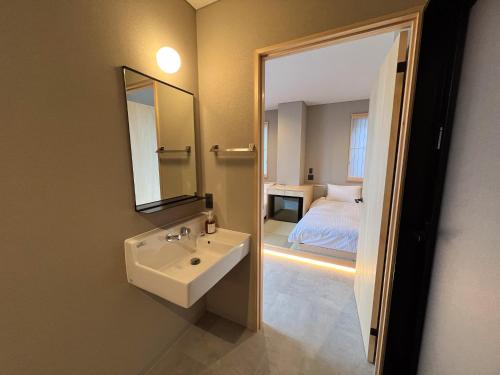 a bathroom with a sink and a mirror and a bed at 日々の宿 ひねもす in Tamano