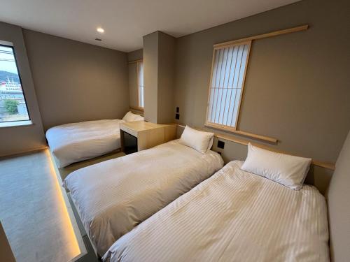 a room with three beds and a window at 日々の宿 ひねもす in Tamano