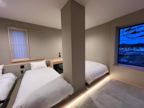 a hotel room with two beds and a large window at 日々の宿 ひねもす in Tamano